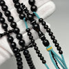 Gros plan perles en Yusr noir avec ficelle turquoise - polissage artisanal